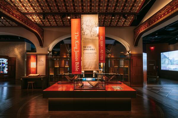 L’intérieur d’un musée, avec une vitrine exposant la Bible du roi Jacques, entourée de panneaux d’information et de banderoles.