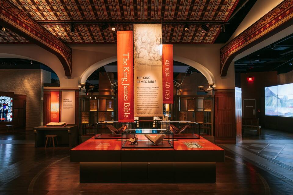 A museum interior with a display case containing the King James Bible, surrounded by informational panels and banners.