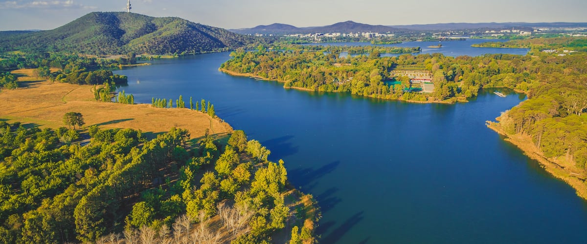 A river winding through a forested landscape with hills in the background and a tower on a hill.
