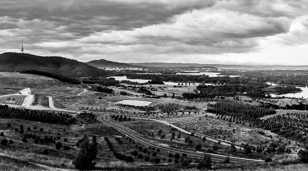 A mountainous landscape with a large dome-shaped building, a winding road, and a distant tower.