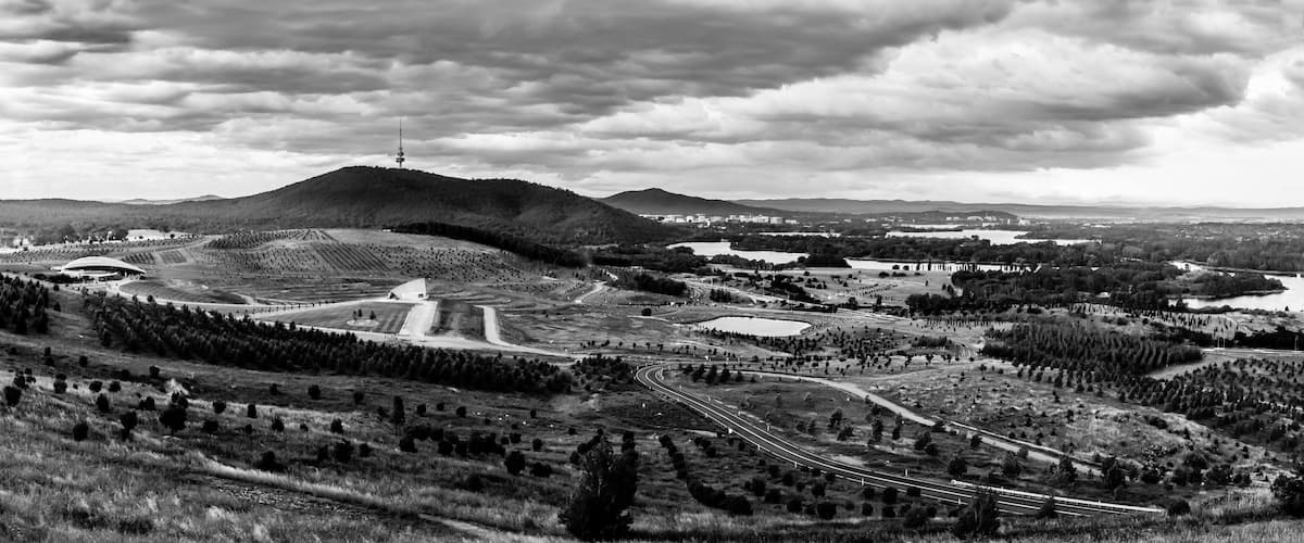 A mountainous landscape with a large dome-shaped building, a winding road, and a distant tower.