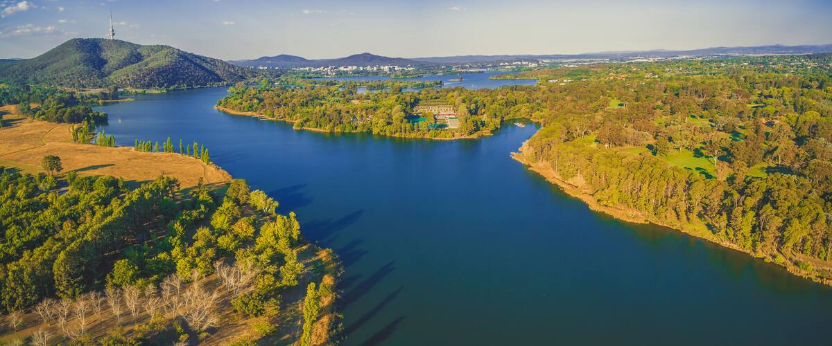 A river winding through a green landscape with hills and a distant tower.