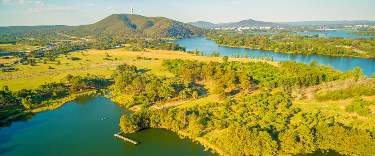 A river winding through a green landscape with hills in the distance and a tower on one of the hills.