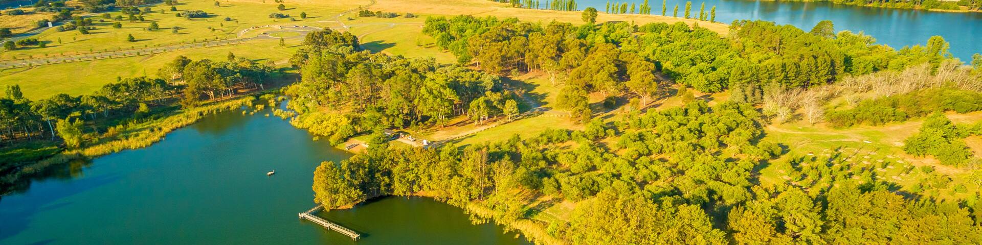 A river winding through a green landscape with hills in the distance and a tower on one of the hills.