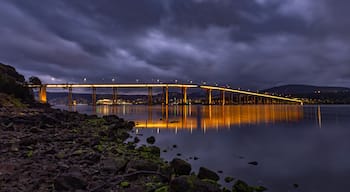 A bridge at night with lights reflecting on the water.