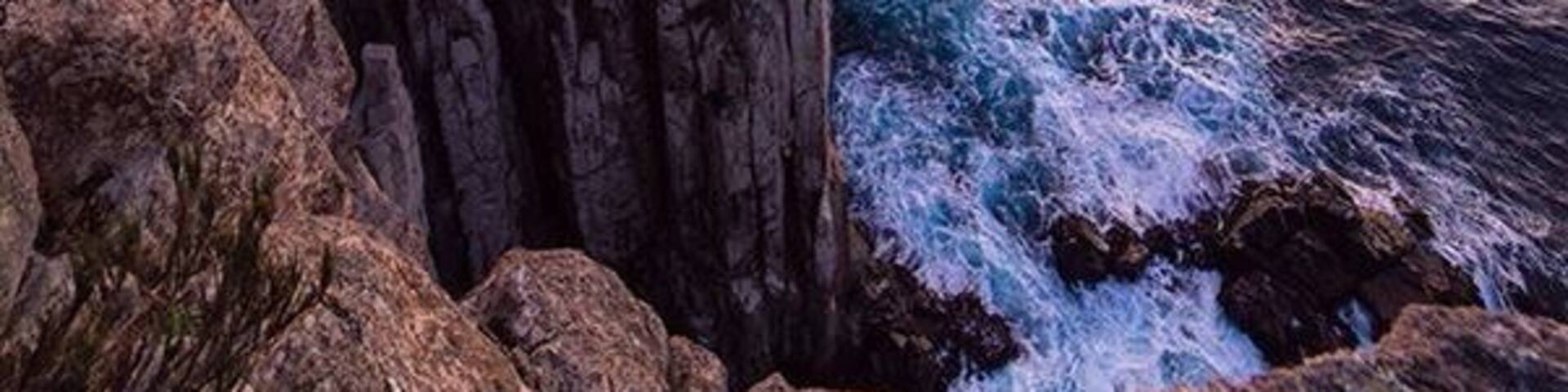 A rugged cliff by the sea at sunset.