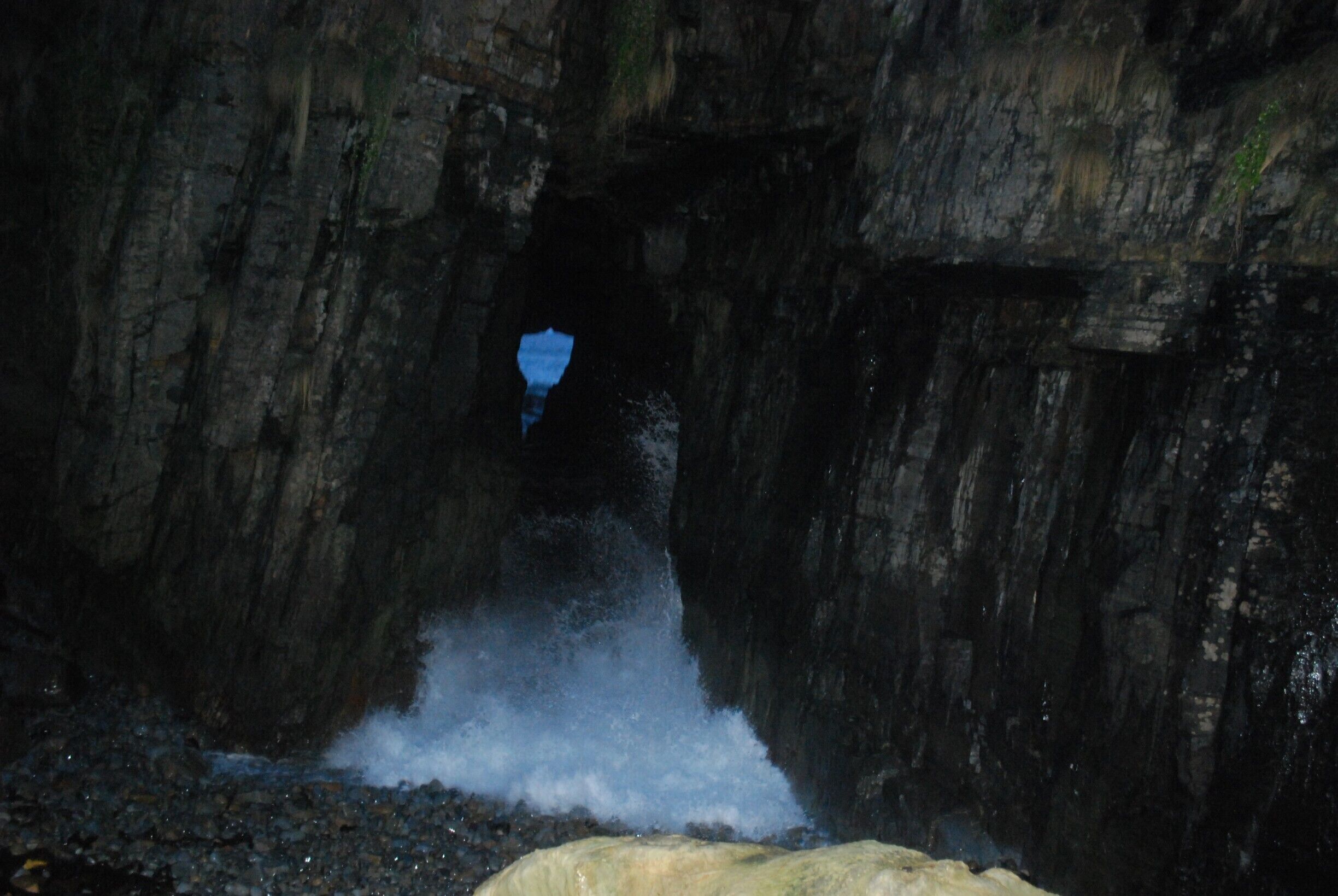A cave entrance with water flowing into it.