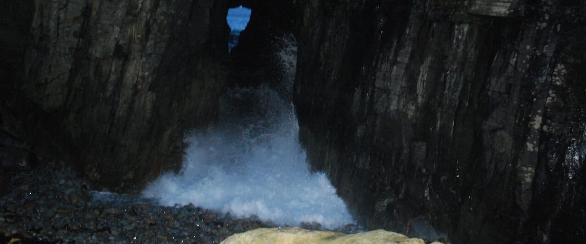 A cave entrance with water flowing into it.