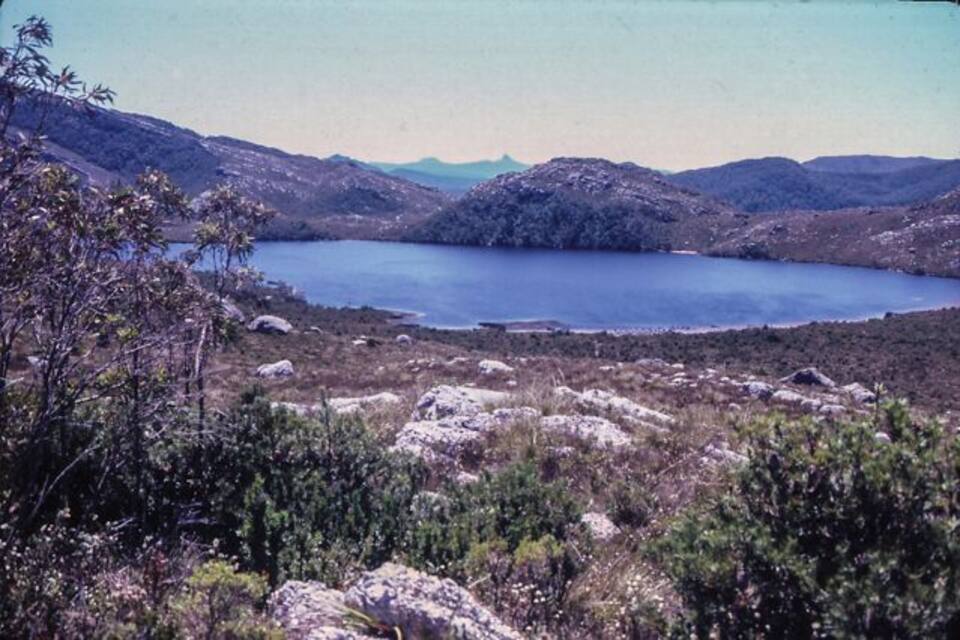 Un lac entouré de collines et d’une végétation clairsemée.