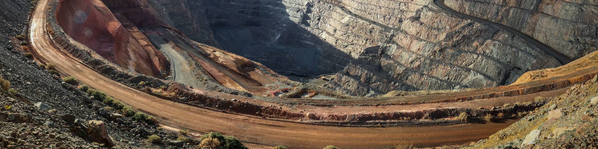 A large open-pit mine with steep, terraced walls and a winding road.