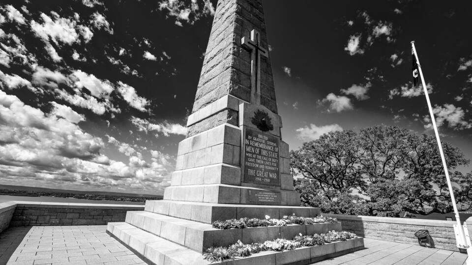 A memorial monument with inscriptions, steps, and a flagpole.