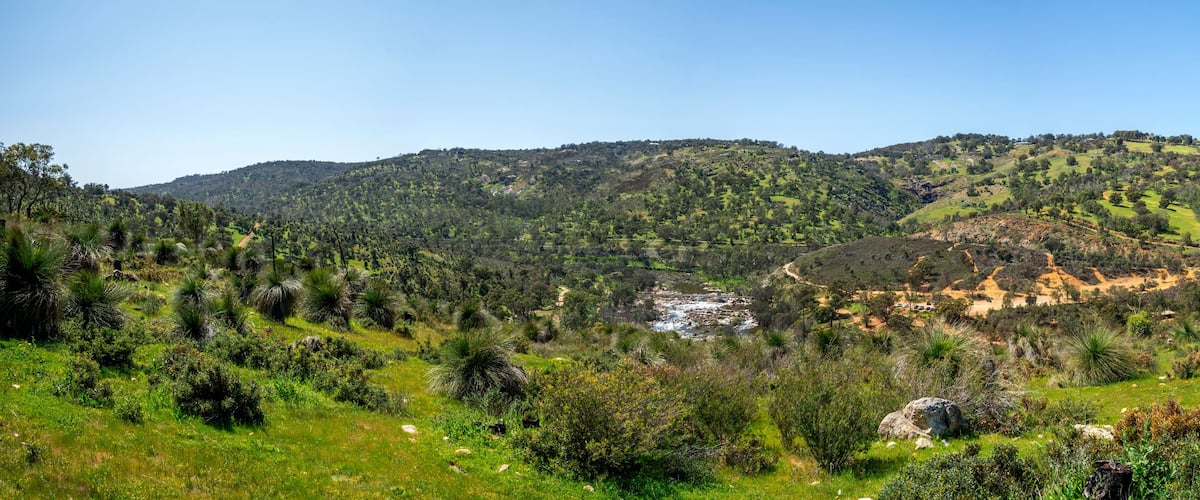 A lush green valley with rolling hills and a river winding through the landscape.