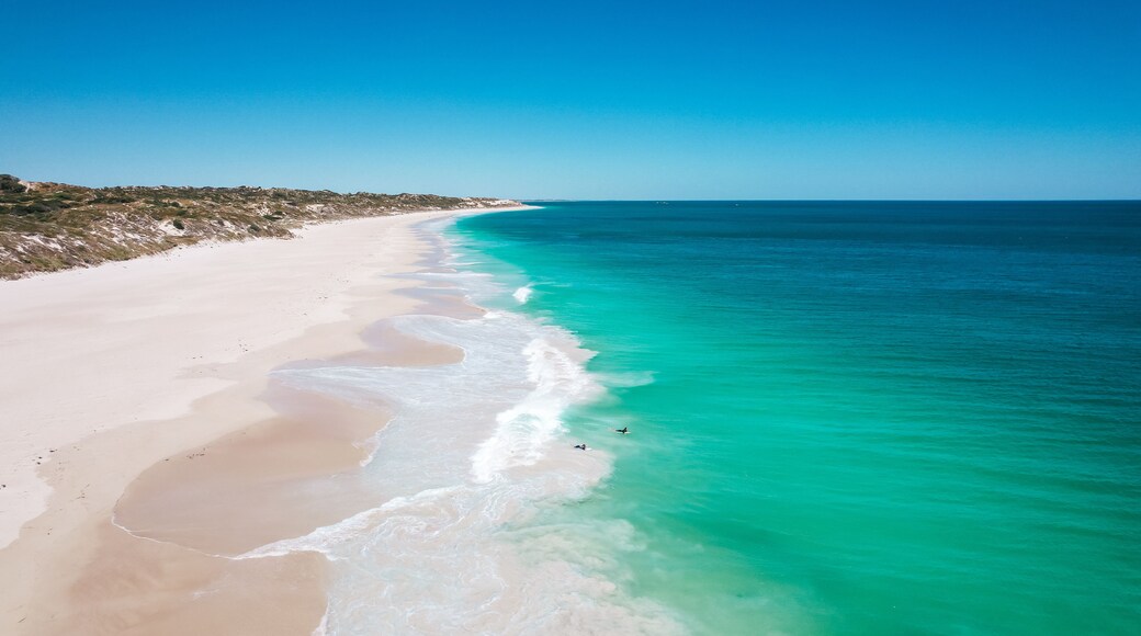 A beach with clear turquoise waters and a sandy shoreline.