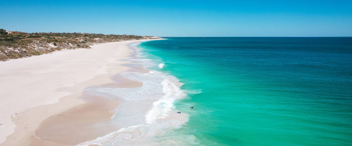 A beach with clear turquoise waters and a sandy shoreline.