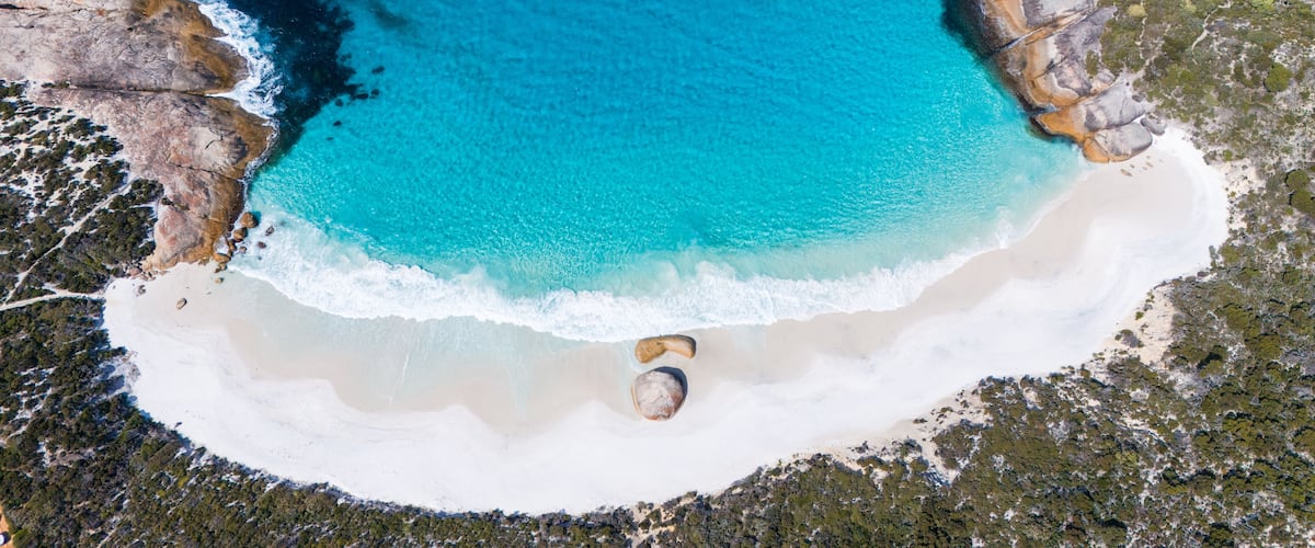 Un paisaje costero con aguas turquesas cristalinas, playas arenosas y afloramientos rocosos.