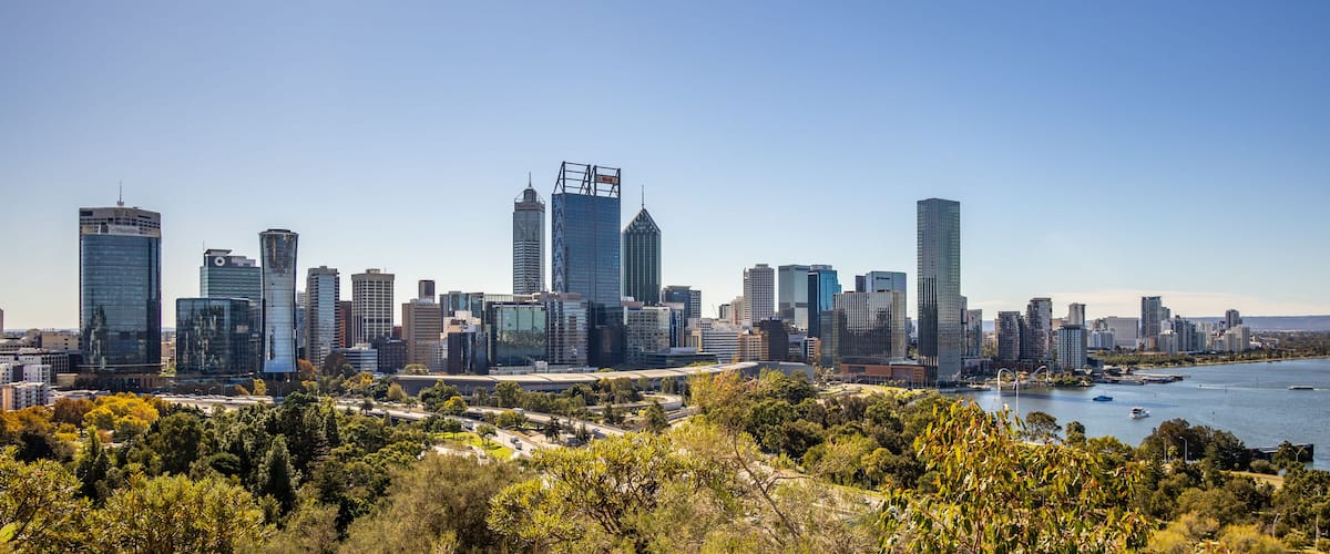 A city skyline with modern skyscrapers, a river, and surrounding greenery.