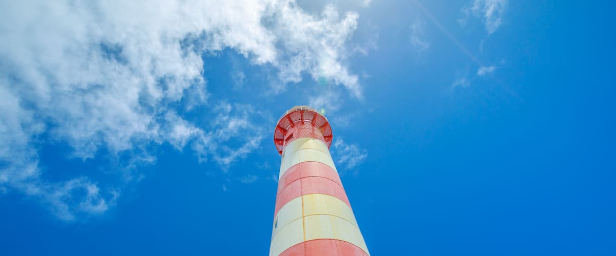Un faro alto y a rayas contra un cielo azul despejado.