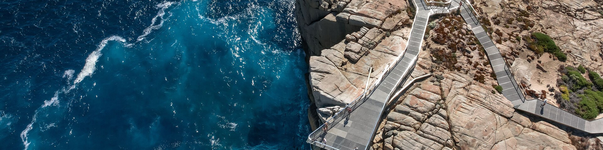 A coastal cliff with a winding pathway and a rocky shoreline.