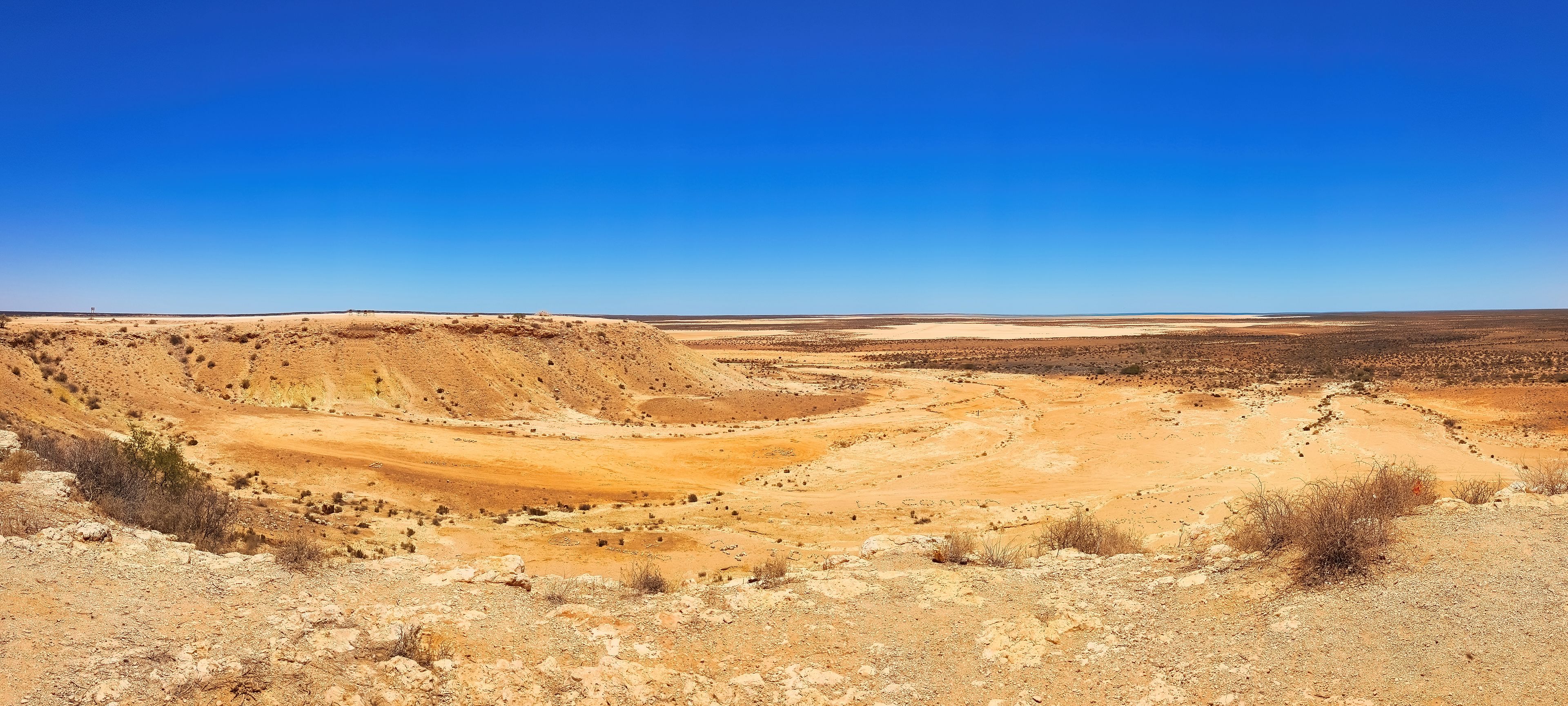 A vast desert landscape with rolling hills and sparse vegetation.