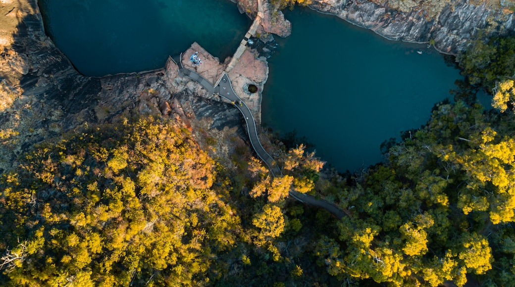 An aerial view of a mountainous area with two lakes, a winding road, and dense forest.