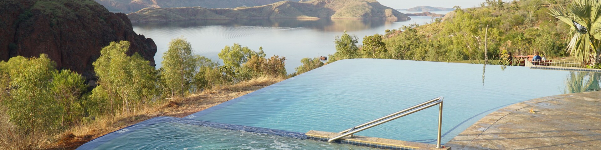 Una piscina con vistas a montañas y un lago.