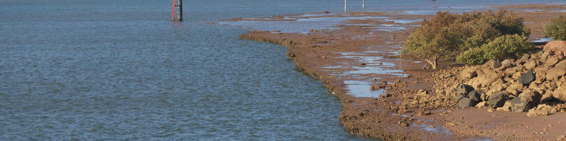Un gran carguero anclado cerca de una costa rocosa con aguas tranquilas.