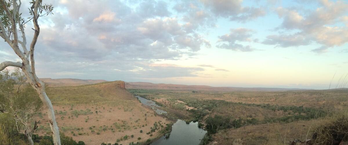 A river winding through a dry, hilly landscape with sparse vegetation and a few trees.