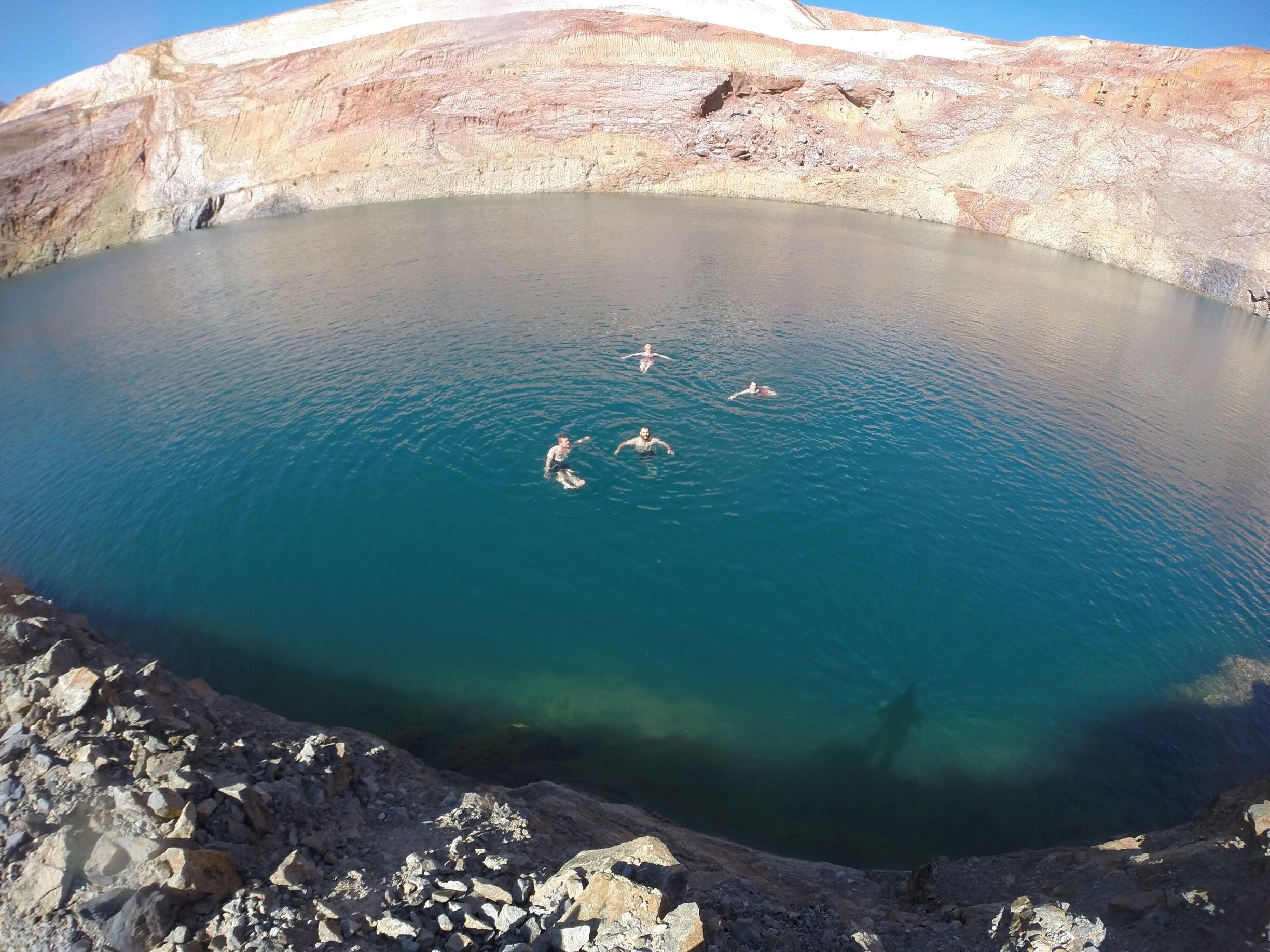 A large, clear blue lake surrounded by rocky terrain.