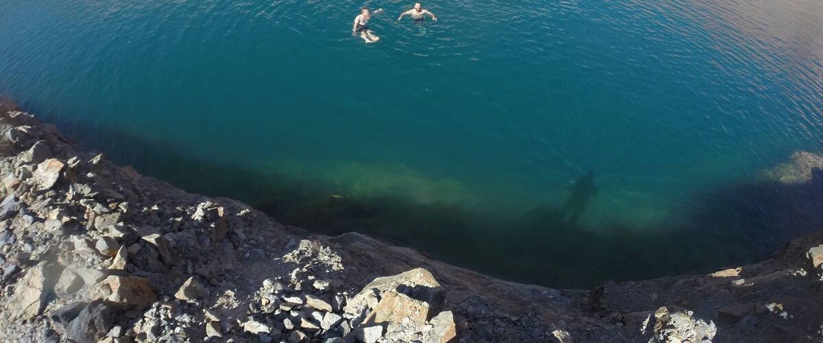 A large, clear blue lake surrounded by rocky terrain.