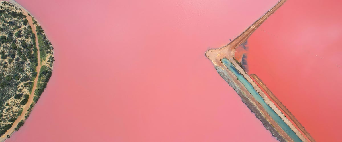 An aerial view of a pink landscape with a distinct boundary line and a patch of greenery.