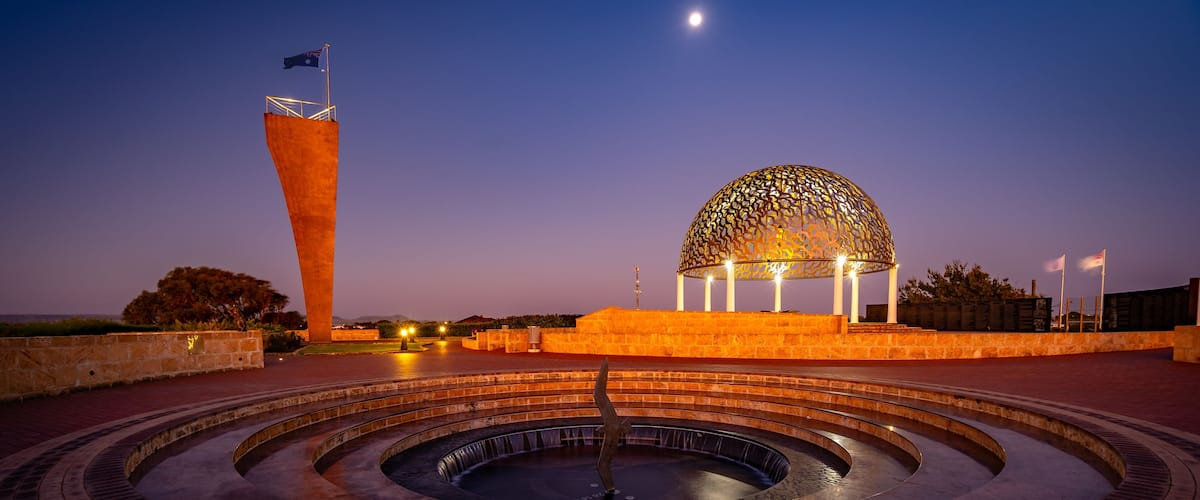 A circular water feature with a central fountain, a large dome structure, and a flagpole with a flag.