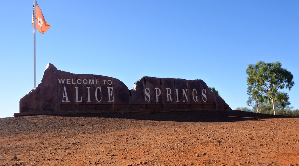 A welcome sign for Alice Springs with a flagpole and a clear blue sky.