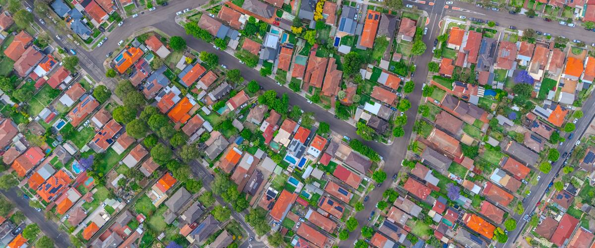 An aerial view of a residential area with houses, streets, and green spaces.