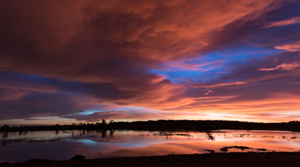 Un coucher de soleil sur un lac paisible, avec des nuages aux couleurs éclatantes.