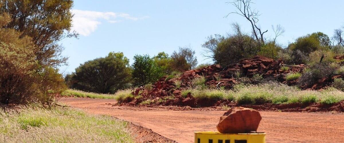 A dirt road with a yellow sign that reads "LIFT UM FOOT".