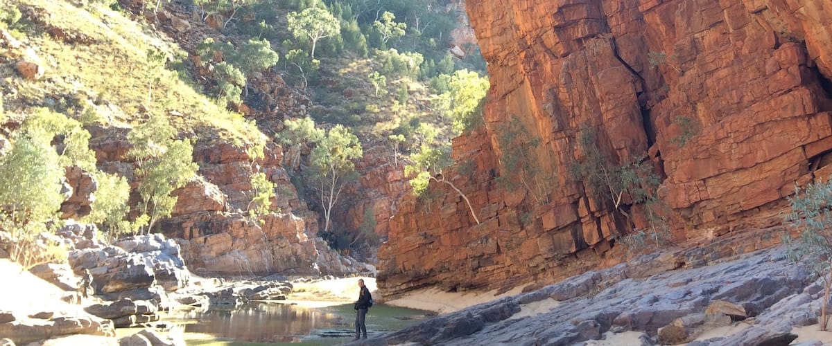 A canyon with red rock formations and a small body of water.