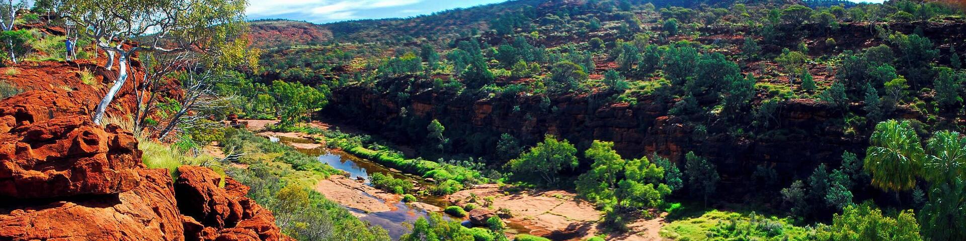 A river flowing through a canyon with red rock formations and green vegetation.