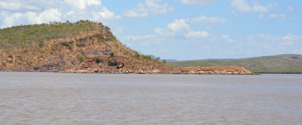 A calm lake with a rocky island covered in sparse vegetation.