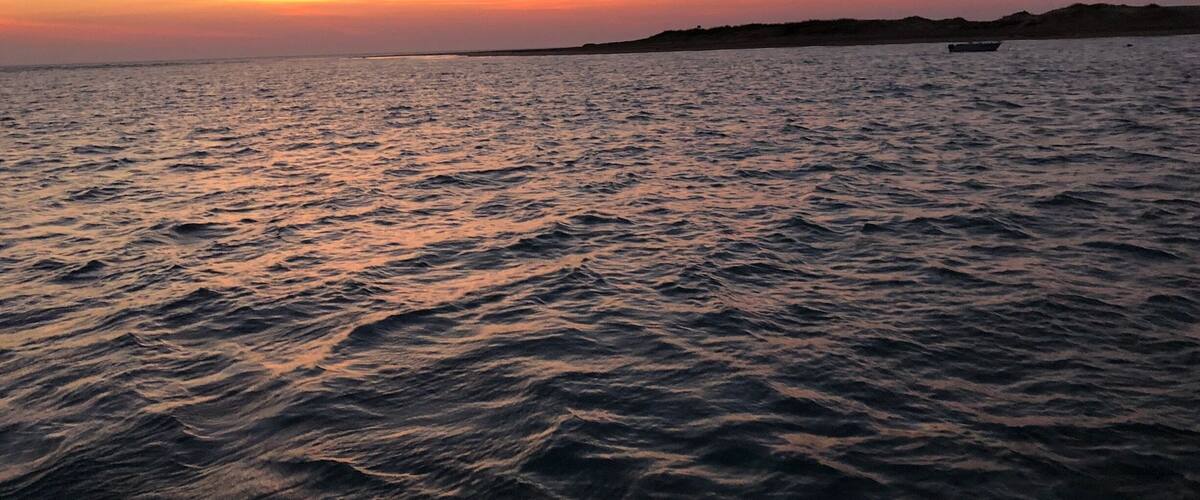 A sunset over a calm sea with gentle waves.
