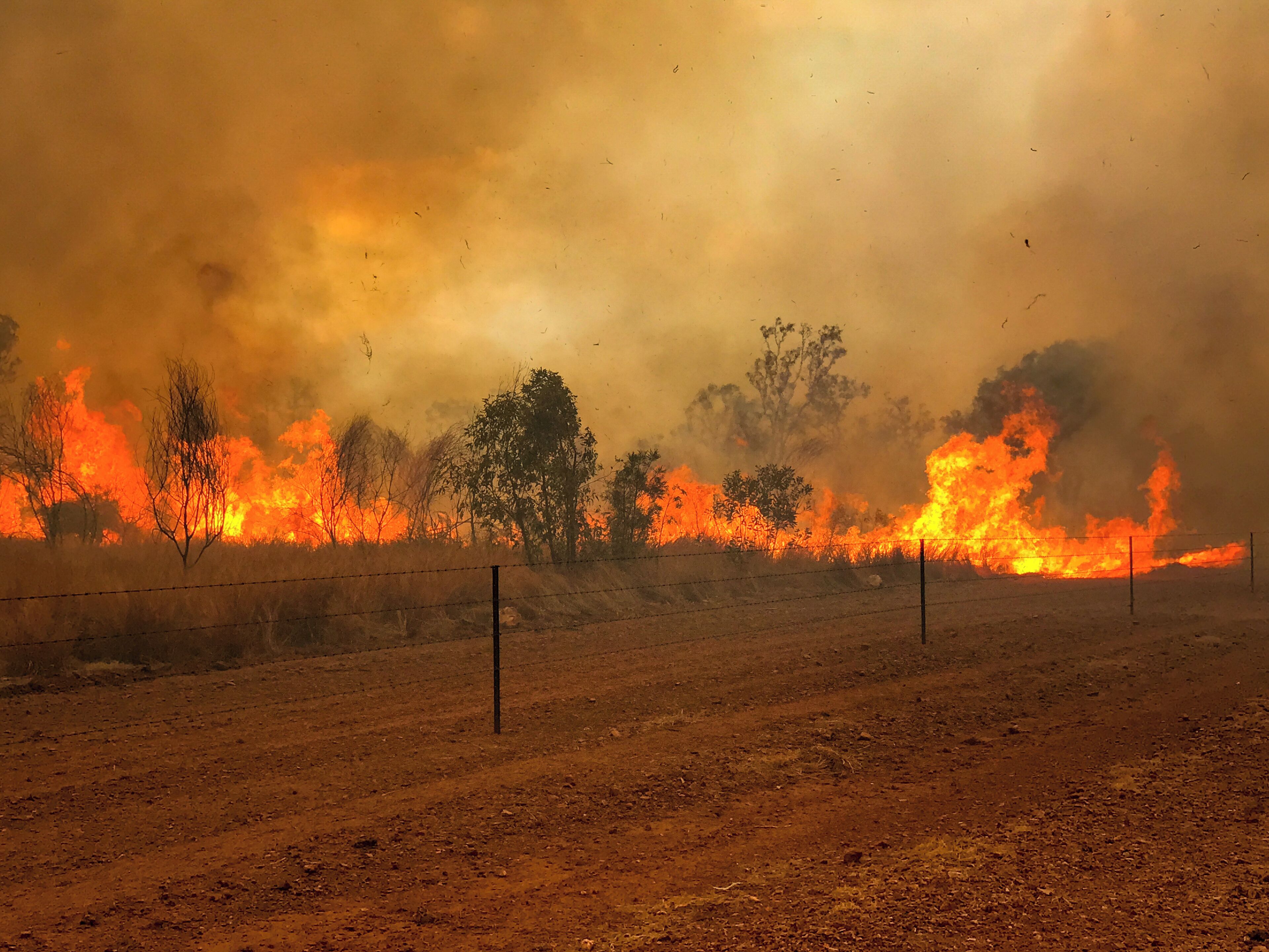 A wildfire with intense flames and smoke in a dry, open field.