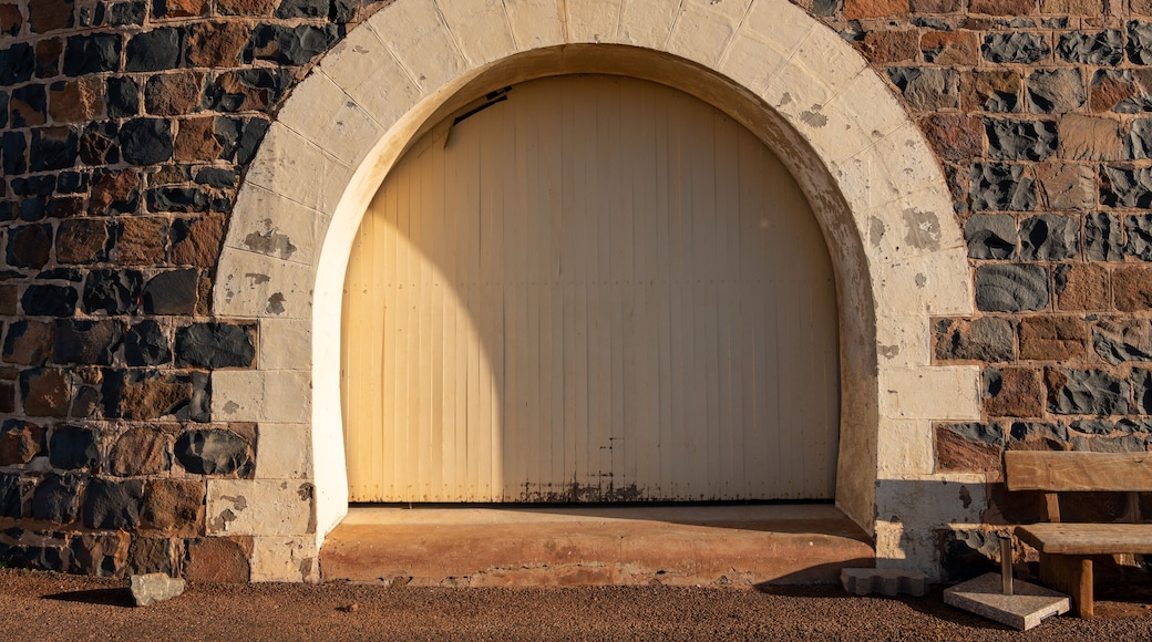 A stone archway with a wooden door, a bench, and a gravel path.