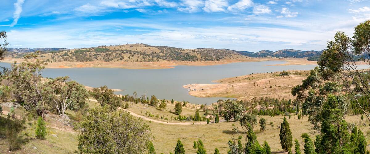 A lake surrounded by hills and sparse vegetation.