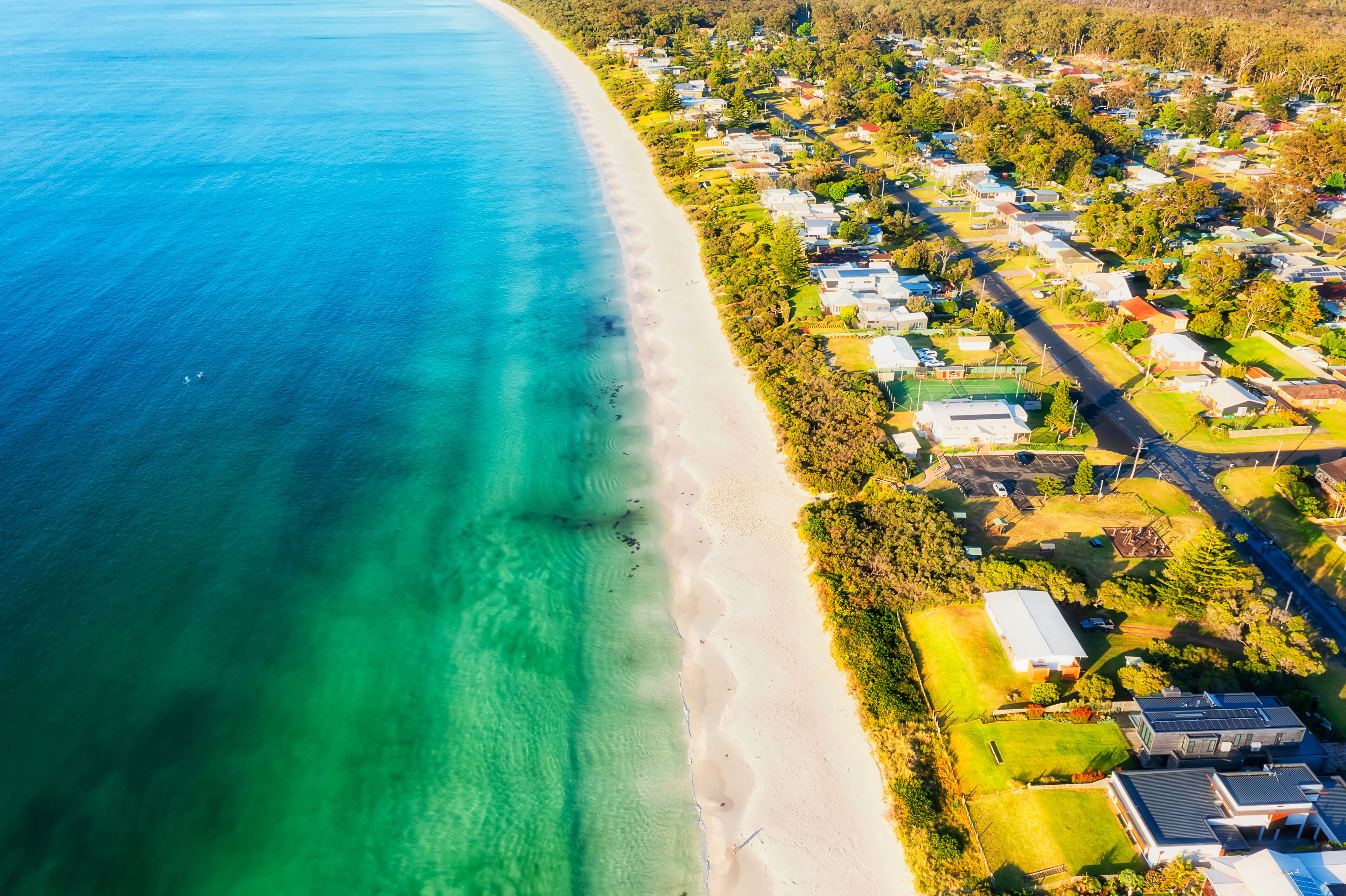 A coastal residential area with a clear beach and houses.