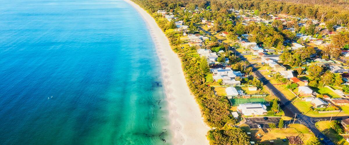 A coastal residential area with a clear beach and houses.
