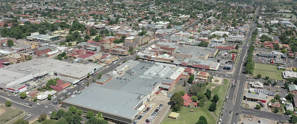 A densely populated urban area with a mix of commercial and residential buildings, a prominent road intersection, and surrounding green spaces.