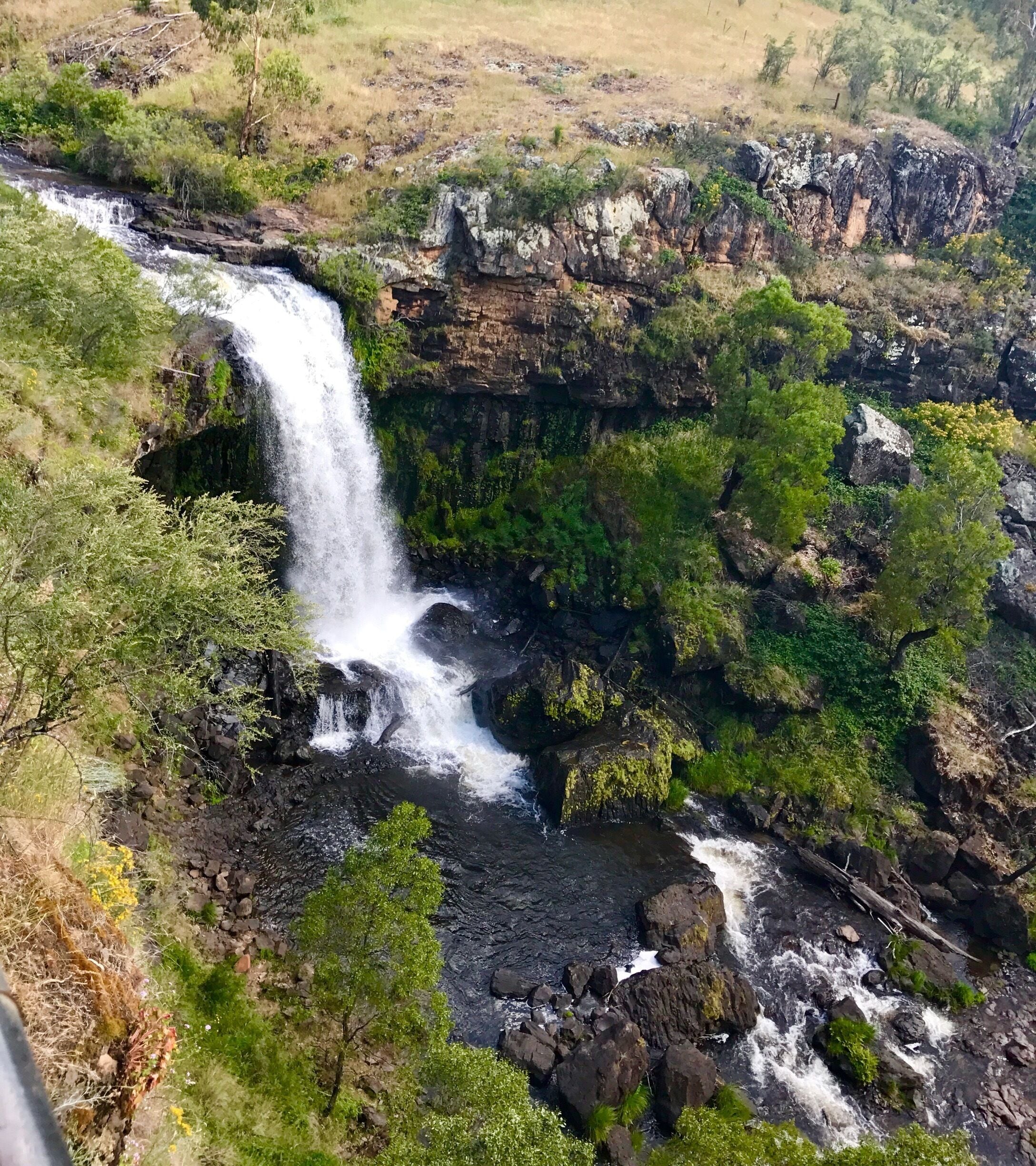 A waterfall cascading over rocky terrain surrounded by lush greenery.