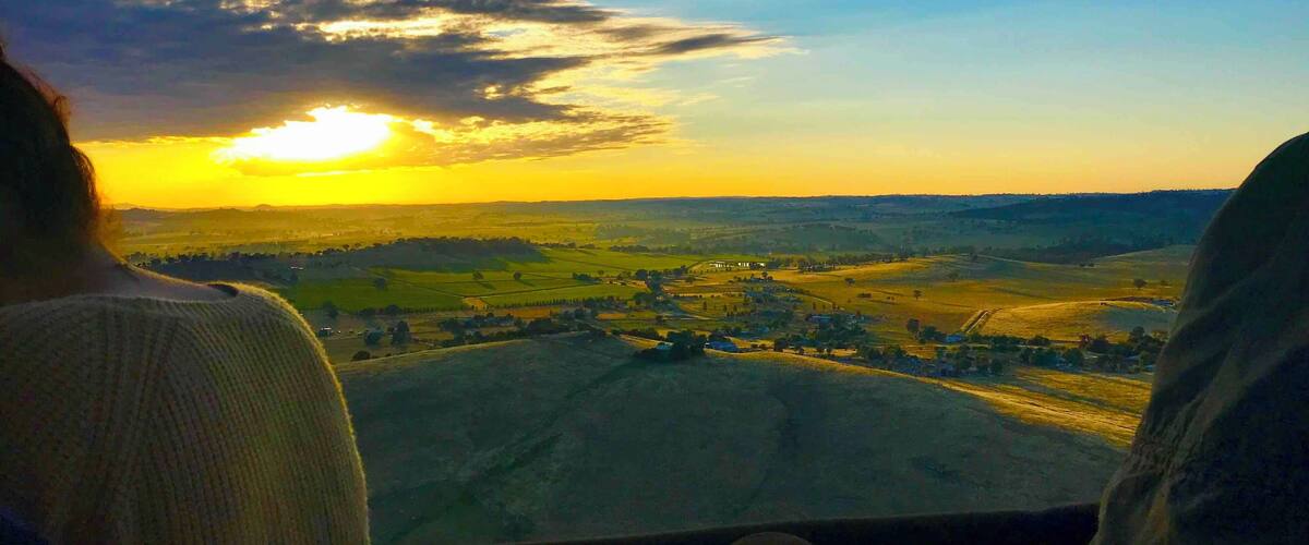 A sunset over a rural landscape with fields and a distant village.