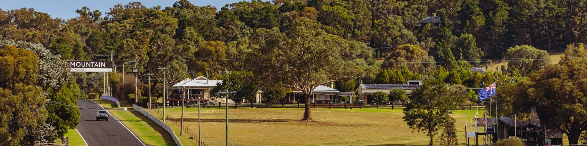 A racetrack with a sign reading 'MOUNT THIRST' and a forested hill in the background.