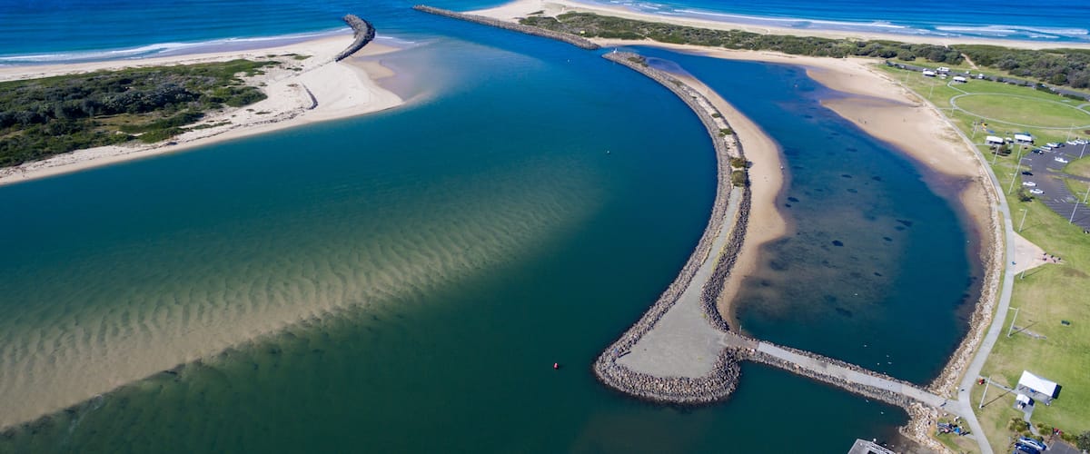 An aerial view of a coastal area with a curved waterway, a small island, and a beach.