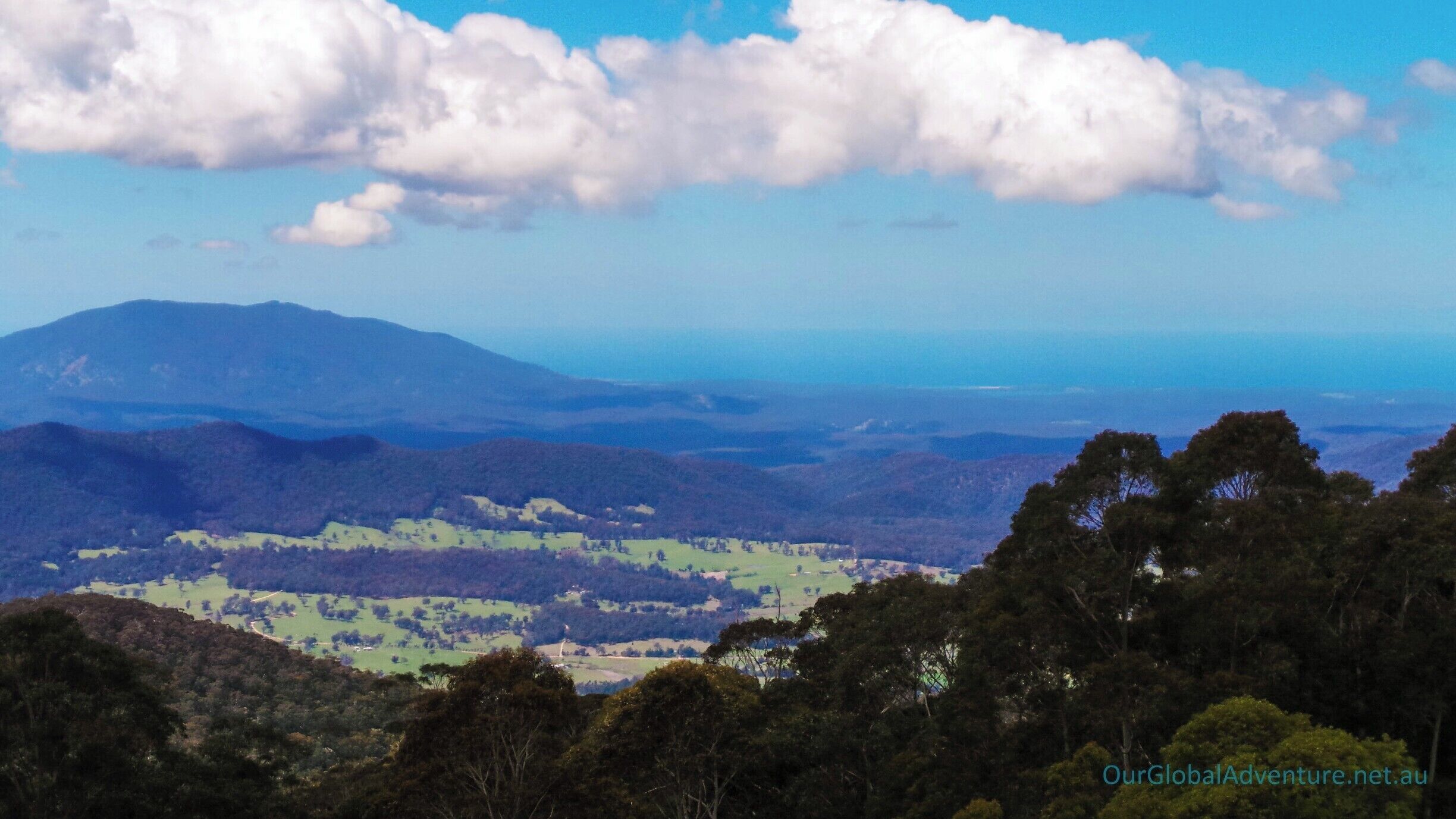 A mountainous landscape with a clear sky and scattered clouds.